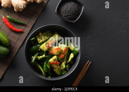 Salade asiatique épicée de concombre avec feuilles de coriandre, gingembre, piment, vinaigre sur fond noir.Concombres épicés.Hors-d'œuvre chinois populaire Banque D'Images