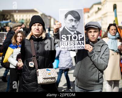 Munich, Allemagne. 09th avril 2022. Garçon avec un signe montrant Poutine comme Hitler lit: ' Stop Russain agression '. Le 9 avril, 2022 mille personnes se sont rassemblées à Munich, en Allemagne, pour protester contre l'invasion russe en Ukraine et se sont remébérées des morts du massacre de Bucha. (Photo par Alexander Pohl/Sipa USA) crédit: SIPA USA/Alay Live News Banque D'Images