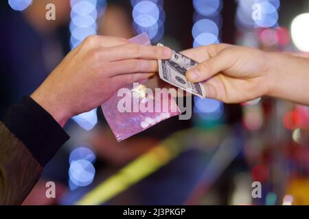 La fête commence à se passer. Gros plan d'une femme qui achète de l'ecstasy chez un concessionnaire dans une discothèque. Banque D'Images