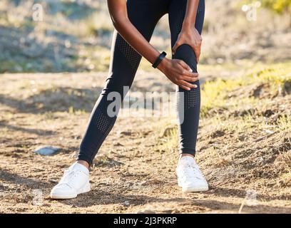 Étirez-vous au-delà de la douleur. Prise de vue d'une femme souffrant de douleurs au genou tout en travaillant dans la nature. Banque D'Images