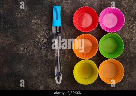 Brosse en silicone et moules à cupcake en silicone, gros plan, sur fond sombre Banque D'Images