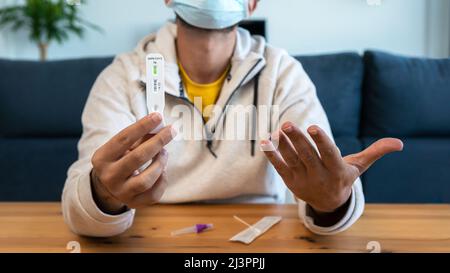 L'homme caucasien fabrique un dispositif de test rapide à domicile pour le virus Covid19 avec un résultat positif. Cassette d'antigène de test PCR express pour la nouvelle variante d'Omicron vi Banque D'Images