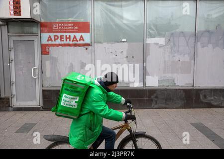 Moscou, Russie. 9th avril 2022. Les coursiers du populaire service de livraison de nourriture "Delivery Club" livrent une commande sur fond de bureau fermé et de bannière avec l'inscription "Rent" dans le centre de Moscou, Russie Banque D'Images