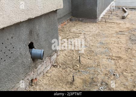 Un tuyau en plastique pour l'évacuation de l'eau de pluie installé à la base de la maison. Sable, gravier et fer de renforcement à la base de la maison, le processus de Banque D'Images