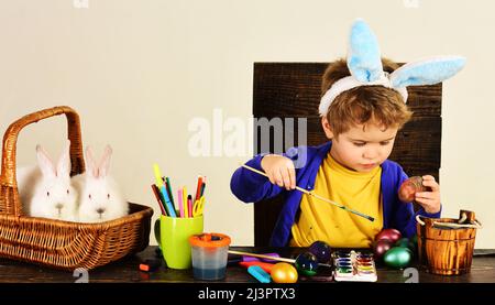 Un enfant dans des oreilles de lapin décorent les œufs de Pâques. Créativité des enfants. Décoration des œufs. Vacances de printemps. Banque D'Images