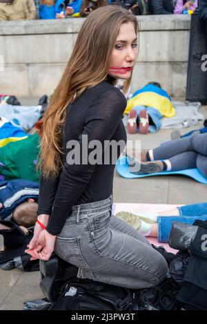 Whitehall, Londres, Royaume-Uni. 9th avril 2022. Les manifestants ont manifesté contre la mort de civils ukrainiens pendant la guerre contre la Russie en jouant à mort, certains ayant leurs mains derrière le dos reproduisant la manière dont des corps ont été trouvés dans les rues. Femme avec les mains attachées derrière son dos et de faux sang Banque D'Images