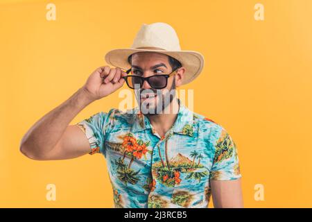 Jeune barbu latino-américain en vêtements de plage regardant latéralement orange fond moyen gros plan concept de vacances. Photo de haute qualité Banque D'Images