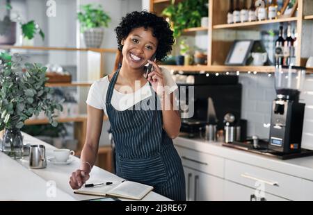 Commander des stocks supplémentaires auprès de ses fournisseurs de confiance. Portrait d'une jeune femme parlant sur un téléphone portable tout en travaillant dans un café. Banque D'Images