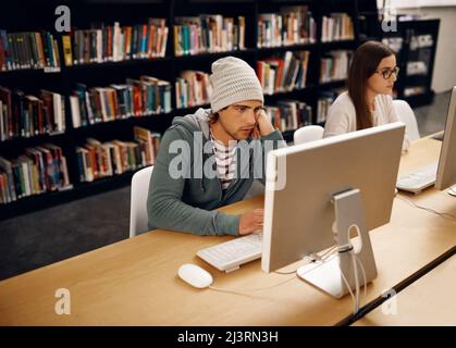 Son heure d'examen. Photo en grand angle de deux jeunes étudiants de l'université qui étudient dans la bibliothèque. Banque D'Images