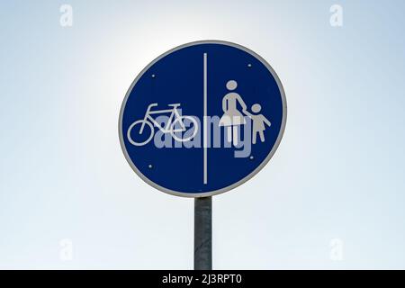 Un panneau de signalisation de chemin partagé en face du ciel bleu clair. Une plaque métallique ronde bleue en Allemagne. Ce symbole indique un chemin pour les cyclistes et les piétons Banque D'Images
