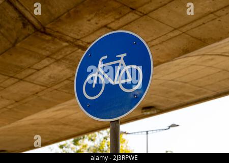Un panneau de signalisation à vélo en face d'un bâtiment. Une plaque métallique ronde bleue pour indiquer un chemin de cycle dans une ville allemande. Ce symbole indique les trajets du cycliste. Banque D'Images