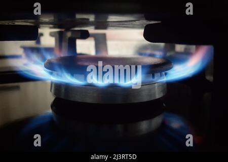 Un brûleur à gaz allumé brûle avec une flamme bleue sur une cuisinière de cuisine. Banque D'Images