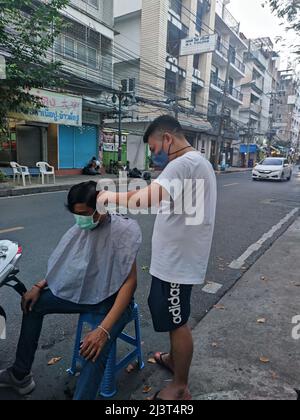 Bangkok, Thaïlande - janvier 22th 2022 : coiffeur de rue coiffant un homme à l'aide de la tondeuse à cheveux Banque D'Images