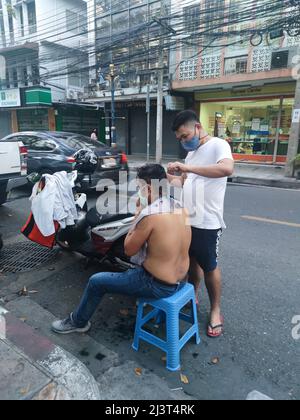Bangkok, Thaïlande - janvier 22th 2022 : coiffeur de rue coiffant un homme à l'aide de la tondeuse à cheveux Banque D'Images