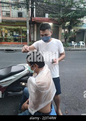 Bangkok, Thaïlande - janvier 22th 2022 : coiffeur de rue coiffant un homme à l'aide de la tondeuse à cheveux Banque D'Images