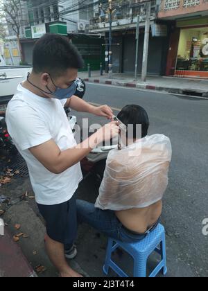 Bangkok, Thaïlande - janvier 22th 2022 : coiffeur de rue coiffant un homme à l'aide de la tondeuse à cheveux Banque D'Images