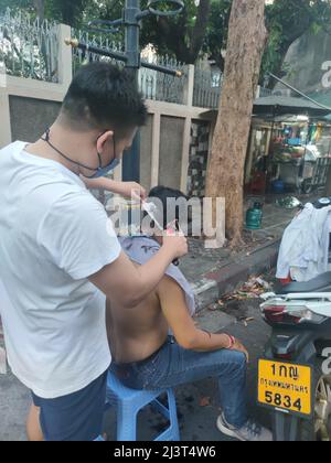 Bangkok, Thaïlande - janvier 22th 2022 : coiffeur de rue coiffant un homme à l'aide de la tondeuse à cheveux Banque D'Images