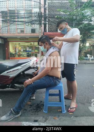 Bangkok, Thaïlande - janvier 22th 2022 : coiffeur de rue coiffant un homme à l'aide de la tondeuse à cheveux Banque D'Images