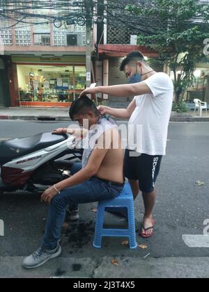 Bangkok, Thaïlande - janvier 22th 2022 : coiffeur de rue coiffant un homme à l'aide de la tondeuse à cheveux Banque D'Images