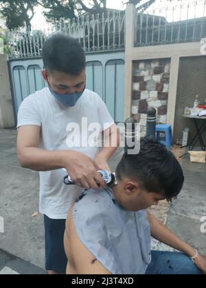 Bangkok, Thaïlande - janvier 22th 2022 : coiffeur de rue coiffant un homme à l'aide de la tondeuse à cheveux Banque D'Images