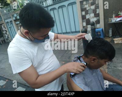 Bangkok, Thaïlande - janvier 22th 2022 : coiffeur de rue coiffant un homme à l'aide de la tondeuse à cheveux Banque D'Images
