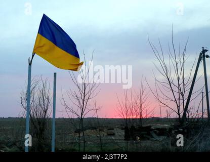 Le drapeau national ukrainien flotte dans l'une des colonies libérées de la région de Kiev, dans le centre-nord de l'Ukraine, le 7 avril 2022. Les troupes russes qui se retirent du nord de l'Ukraine ont laissé derrière elles des bâtiments écrasés, des rues jonchée de voitures détruites et des résidents qui ont cruellement besoin de nourriture et d'autres aides, des images qui ont alimenté les appels de Kiev jeudi à davantage d'aide occidentale pour mettre fin à la prochaine offensive de Moscou. Photo de Yuliia Ovsyannikova/Ukrinform/ABACAPRESS.COM Banque D'Images