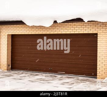 Porte de garage marron dans une maison privée en hiver. Banque D'Images