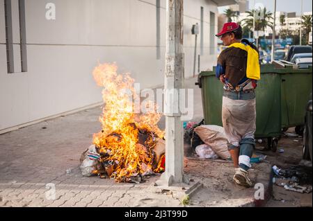 Sousse, Tunisie-09/17/2019: Rue de la ville, Sousse. Un résident local dans des vêtements sales dansant près du feu, près des ordures. Attirer l'attention sur hi Banque D'Images