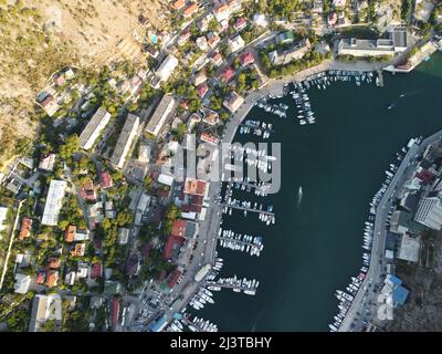 Vue panoramique aérienne du paysage de Balaklava avec des bateaux et la mer dans la baie de la marina au coucher du soleil. Attraction touristique de Crimée Sébastopol. Vue de dessus de drone Banque D'Images