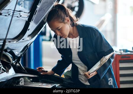 Shell vous donne la meilleure et la moins chère solution pour vos problèmes de voiture. Photo d'une mécanicien travaillant sur une voiture dans un atelier de réparation automobile. Banque D'Images