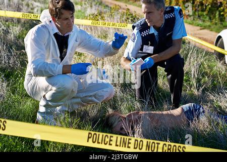 Examen de la preuve. Photo de deux enquêteurs examinant des preuves sur les lieux d'un crime. Banque D'Images