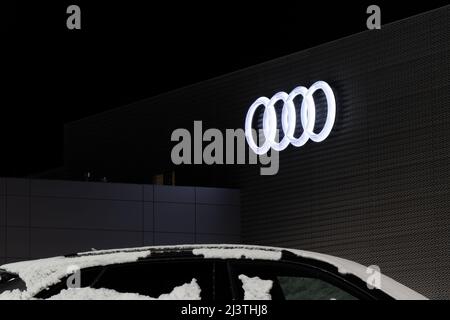 Le célèbre logo Audi à quatre anneaux est illuminé la nuit sur le côté d'un concessionnaire Audi. Banque D'Images