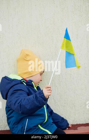 Un petit garçon patriotique porte le drapeau ukrainien. Tenez-vous avec l'Ukraine. Soutenir l'Ukraine. Arrêter le concept d'agression russe. Arrêter la guerre en Ukraine. Priez pour l'Ukraine Banque D'Images