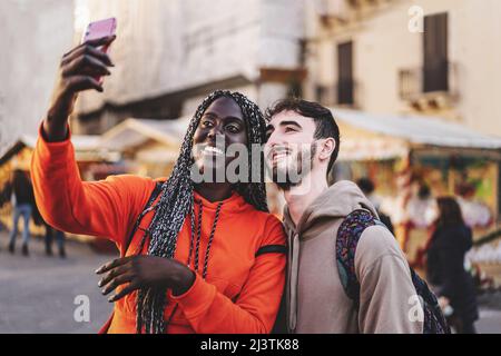 couple interracial de jeunes qui prennent un selfie au marché de la ville - les touristes se faisant des moments de tournage ensemble Banque D'Images
