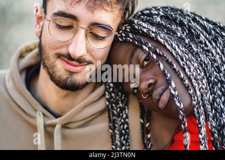 Couple biracial affectueux assis à l'extérieur - gros plan Banque D'Images