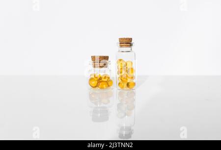 Deux capsules pour l'huile de poisson dans une bouteille en plastique transparent sur fond blanc. Banque D'Images