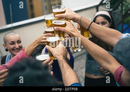 Groupe heureux de jeunes qui toaster avec de la bière. Une fête d'étudiants multiraciale sur la terrasse de l'auberge de jeunesse. Banque D'Images