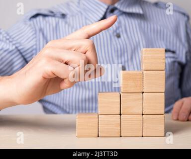 Homme main pointant vers le haut de l'échelle de carrière, habitacle. Escaliers depuis des blocs de bois. Développement professionnel, croissance, concept de promotion. Photo de haute qualité Banque D'Images