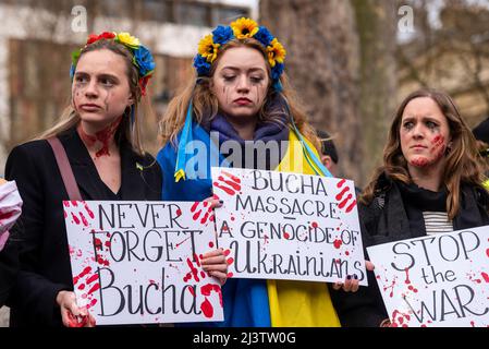 Des manifestants qui mènent une mort-dans, faisant référence aux civils ukrainiens tués dans des villes comme Bucha pendant la guerre avec la Russie. Les femmes avec des messages sanglants Banque D'Images