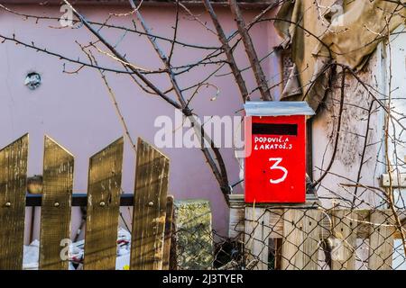 Boîte aux lettres rouge, avec lettres blanches, adresse écrite et numéro de maison sur une clôture en bois. Banque D'Images