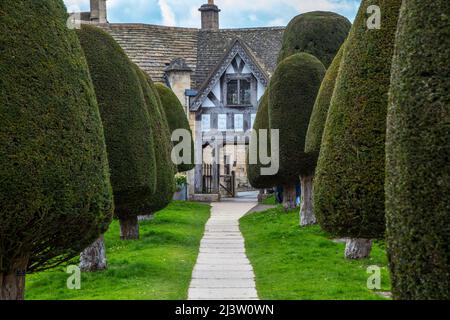 L'entrée de la cour de l'église du village de Painswick et les arbres de l'if dans les Cotswolds, Gloucestershire Banque D'Images