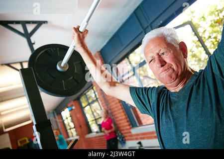 Soyez mentalement plus fort que ce que vous ressentez physiquement. Prise de vue d'un homme senior qui fait de l'entraînement de poids à la salle de gym. Banque D'Images