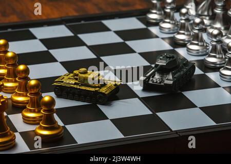 Tanks jouets avec échecs sur échiquier. Concept de stratégie militaire. Banque D'Images