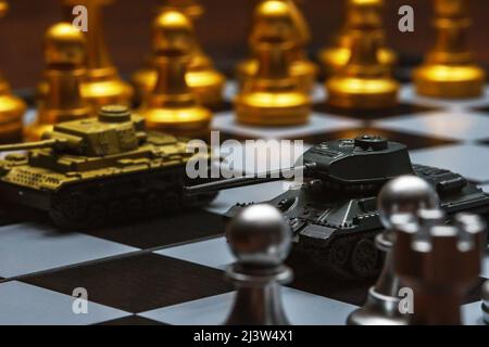 Tanks jouets avec échecs sur échiquier. Concept de stratégie militaire. Banque D'Images