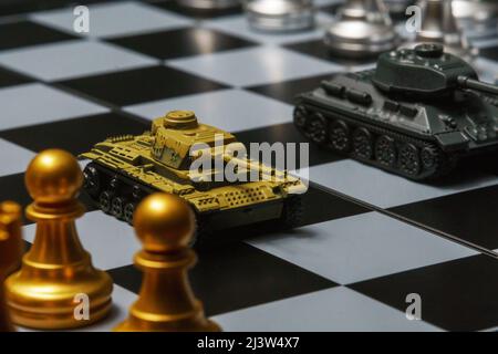 Tanks jouets avec échecs sur échiquier. Concept de stratégie militaire. Banque D'Images