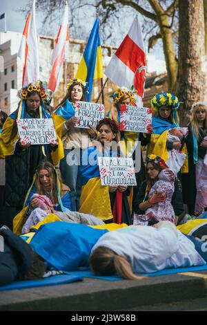 Groupe de femmes pro-ukrainiennes montre à Londres pour la guerre en Ukraine. Entouré de drapeaux ukrainiens, se trouvent sur le sol recouvert de sang, de fleurs Banque D'Images