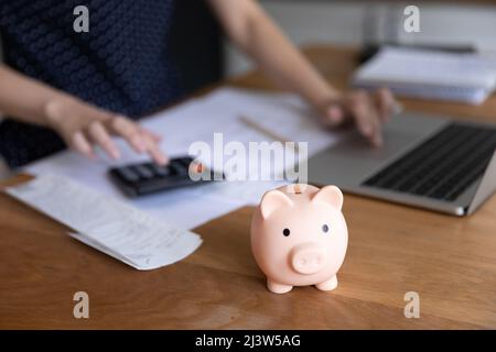 La femme inconnue compte les dépenses, gros plan focus piggybank sur la table Banque D'Images