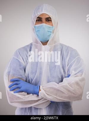 Rester en sécurité pour que je puisse continuer à vous aider. Photo d'un professionnel de la santé debout dans un costume de noisette jetable avec ses bras repliés. Banque D'Images