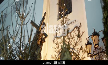 Un beau petit monument avec des guirlandes en feu autour. Action. Un bâtiment blanc avec des branches de sapins à côté duquel il est lumineux Banque D'Images