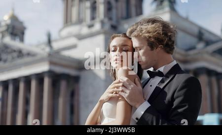 Portrait d'un homme marié embrassant du dos jeune mariée heureuse en robe blanche. Action. Mariage de la photosession en face de la cathédrale Saint Isaac, Saint Banque D'Images